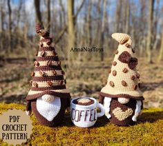 two crocheted christmas trees sitting next to each other on top of a moss covered ground