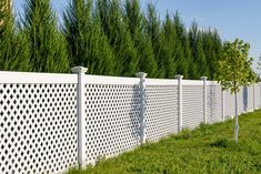 a white privacy fence in front of some trees