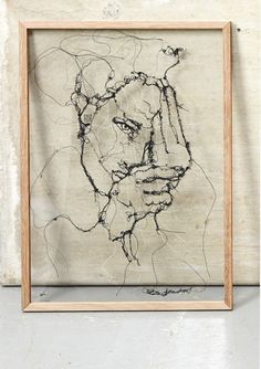 a framed artwork with a man's face drawn in black ink on parchment paper