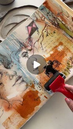 a person is using a red brush to paint an art piece on a book cover