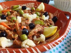 a bowl filled with meat and vegetables on top of a checkered tablecloth covered table