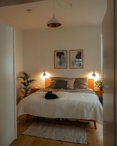 a bed sitting in a bedroom next to two pictures hanging on the wall above it