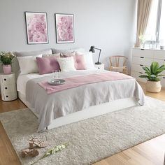 a bedroom with white walls and wooden flooring is pictured in this image, there are two framed pictures on the wall above the bed