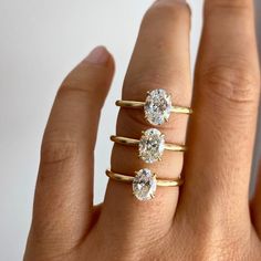 three diamond rings on the finger of a woman's hand, all in yellow gold