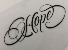 the word hope written in cursive writing on a white surface with black ink