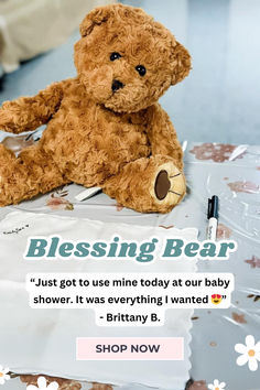 a brown teddy bear sitting on top of a table next to a pen and paper