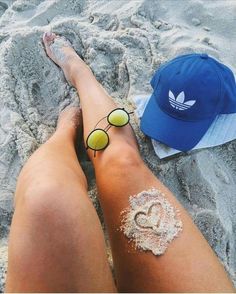 a person with sunburns and sunglasses on their feet in the sand