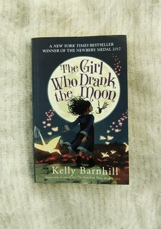 the girl who drank the moon by kelly barnhill is shown on a white blanket