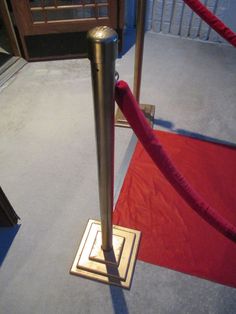 a red carpeted area with a metal pole and rope on the ground next to it