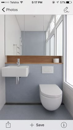 a white toilet sitting next to a bathroom sink under a large mirror in a bathroom