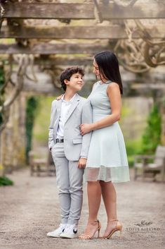 a woman standing next to a boy in a suit