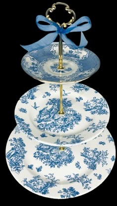 three blue and white plates stacked on top of each other with a ribbon tied around the edge