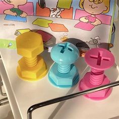 three plastic toys sitting on top of a white table next to a book and bag