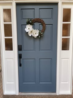 a blue front door with white flowers and a wreath on the side entrance to a home