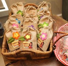 several bags filled with candy sitting on top of a wooden table next to a basket