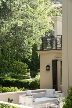 a white couch sitting on top of a patio next to a lush green tree filled forest