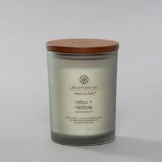 a candle with a wooden lid sitting on a white table next to a gray wall