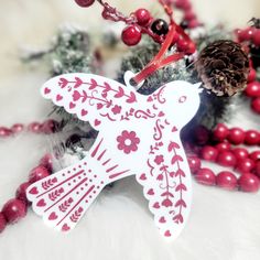 a white bird ornament sitting on top of a table next to red berries