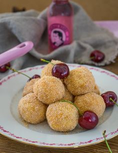 a white plate topped with donuts covered in powdered sugar and cherries next to a pink hairdryer