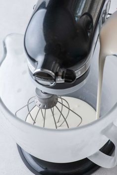 a blender filled with white liquid being poured into it