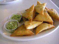 some food is on a white plate with dipping sauces