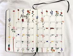 an open planner with flowers on it and the word may written in cursive writing