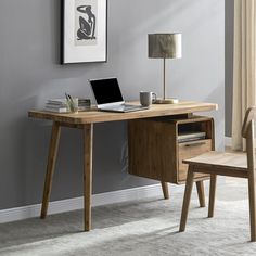 a desk with a laptop on it and a chair next to it in front of a gray wall