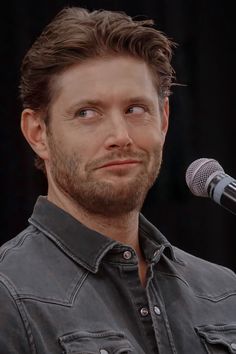 a close up of a person with a microphone in front of him and a black background