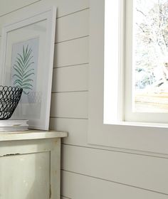 a pineapple print is on the wall next to a white dresser with a black basket