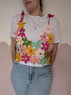 a woman in jeans and a t - shirt with crocheted flowers on it