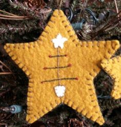 a yellow felt star ornament hanging from a christmas tree