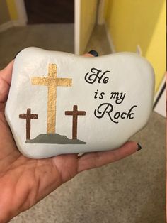 someone holding up a rock with a cross on it that says, he is my rock