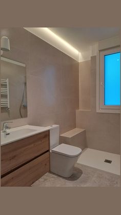 a white toilet sitting next to a sink in a bathroom under a blue sky window