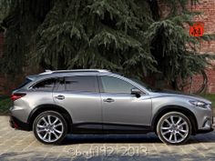 a silver car parked in front of a brick building next to a tree filled parking lot