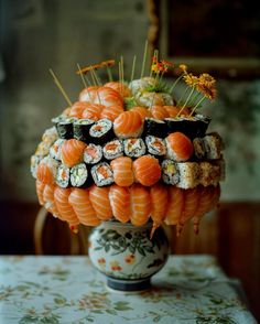 an arrangement of sushi arranged in a vase on top of a table with flowers