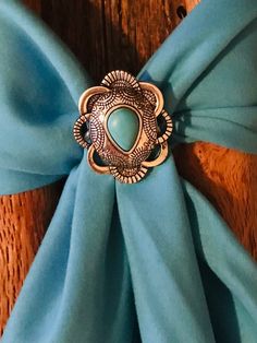 Wild Rag Western concho slide. This one is Aztec  pattern with silver in scalloped shape with pear shaped turquoise stone at center. lThis is a simple slide and will go with all your scarves.  This is smaller Slide measuring  1-1/4 and 1.5" across. Has custom backing to hold scarf made of silver solder and stainless. Please check out our other items as some are complimentary to this item. If you buy 2 or more items you will get 15% off! Spend $50 and get 20% off. We can ship multiple items for one normal shipping cost. We take custom order requests as well. Scarf Slide, Floral Bandana, Wild Rag, Southwestern Design, Cowboy Cowgirl, Aztec Pattern, Cowboy And Cowgirl, Turquoise Stone, Pear Shaped