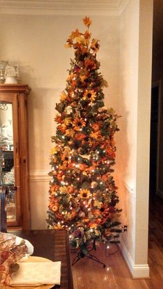 a decorated christmas tree in the corner of a room with wood flooring and white walls