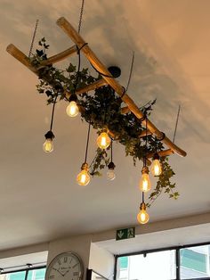 a light fixture made out of wood and hanging from the ceiling with plants growing on it