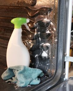 a spray bottle sitting on top of a stove next to a blue towel and green rag