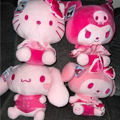 three pink hello kitty stuffed animals sitting on a couch