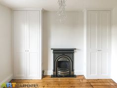 an empty room with a fireplace and white cupboards