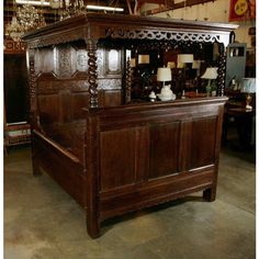 a large wooden bed sitting inside of a room next to a chandelier hanging from the ceiling