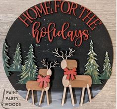 a sign that says home for the holidays with two reindeers in front of trees