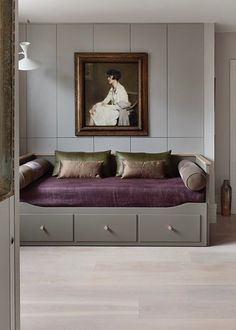 a painting hangs above a bed in a room with white walls and wooden floors, along with drawers