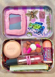 an open lunch box filled with lots of toys and makeup on top of a table