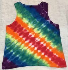 Medium Anvil lightweight unisex 100% cotton tank top tie dyed in a diagonal accordion fold & striped in a mirrored rainbow motif. All of our tie dyed & bleach discharged items are made individually to be one-of-a-kind pieces. We can try to replicate patterns with any other colors, but cannot guarantee the same effects. Tie dyes are unique, so what you see here is what you get - not something similar to this one, but THIS ONE. Summer Striped Cotton Vest, Cotton Tie-dye Tank Top For Festival, Cotton Tie Dye Tank Top For Festivals, Hand Dyed Cotton Tank Top, Spring Tie Dye Cotton Tank Top, Hand Dyed Rainbow Top For Summer, Hand Dyed Rainbow Tops For Spring, Accordion Fold, Diagonal Stripes