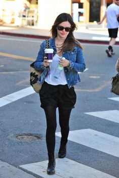 a woman walking across a street holding a cup