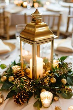 a candle is lit on top of a centerpiece with greenery and pine cones