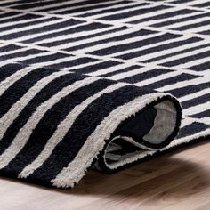 a black and white rug is laying on the floor with it's end rolled up