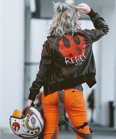 a woman with grey hair wearing orange pants and a black jacket